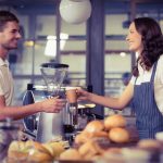 coffee shop worker handing a cup to a customer