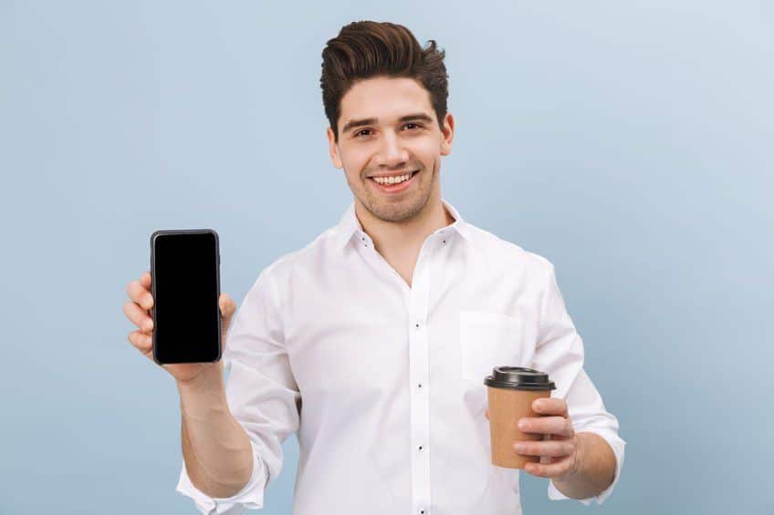 smiling man holding coffee and a phone