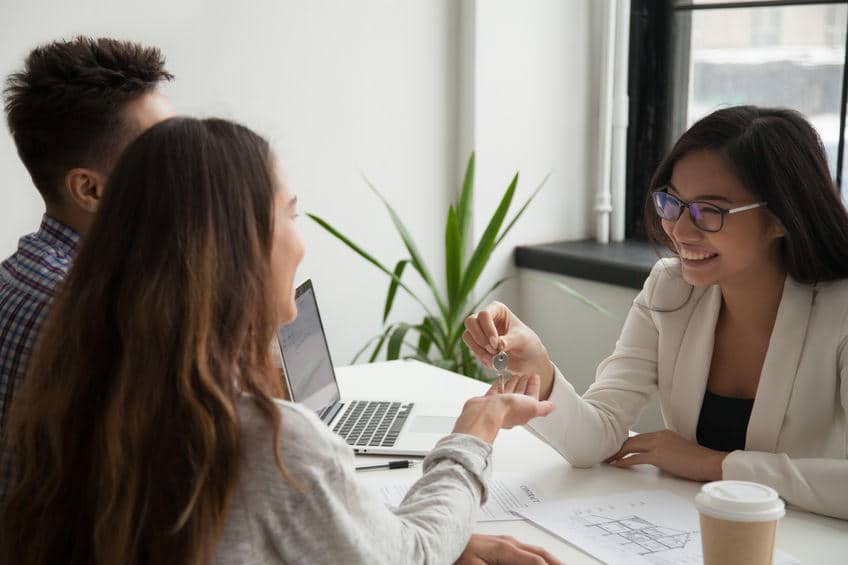 businesswoman speaking with couple at her office desk