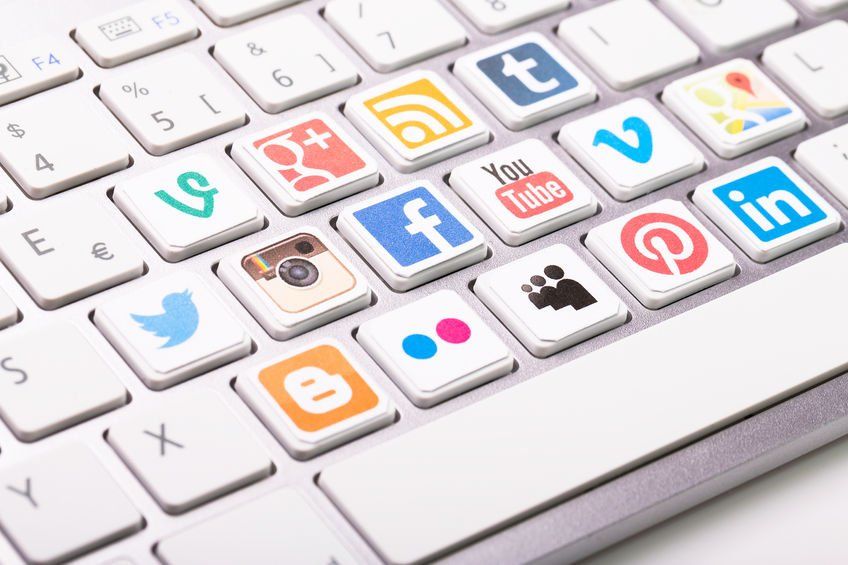 social media icons on a laptop keyboard: Twitter, Facebook, Instagram, YouTube, Pinterest, Tumblr, and more
