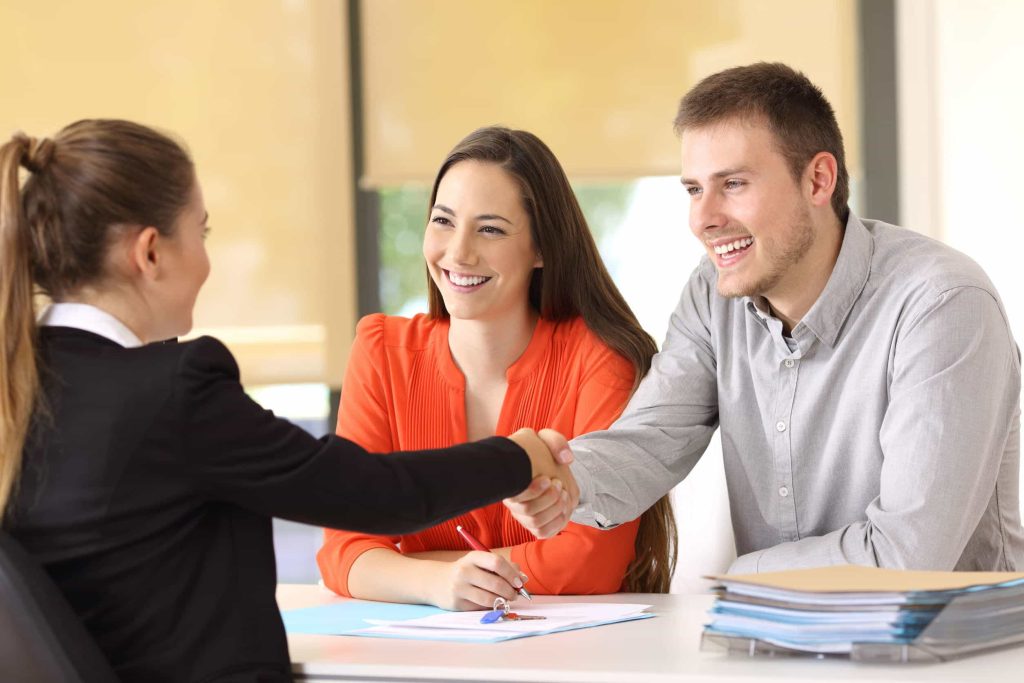 happy customers shaking hands with a businesswoman