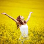 happy woman in a field of yellow flowers