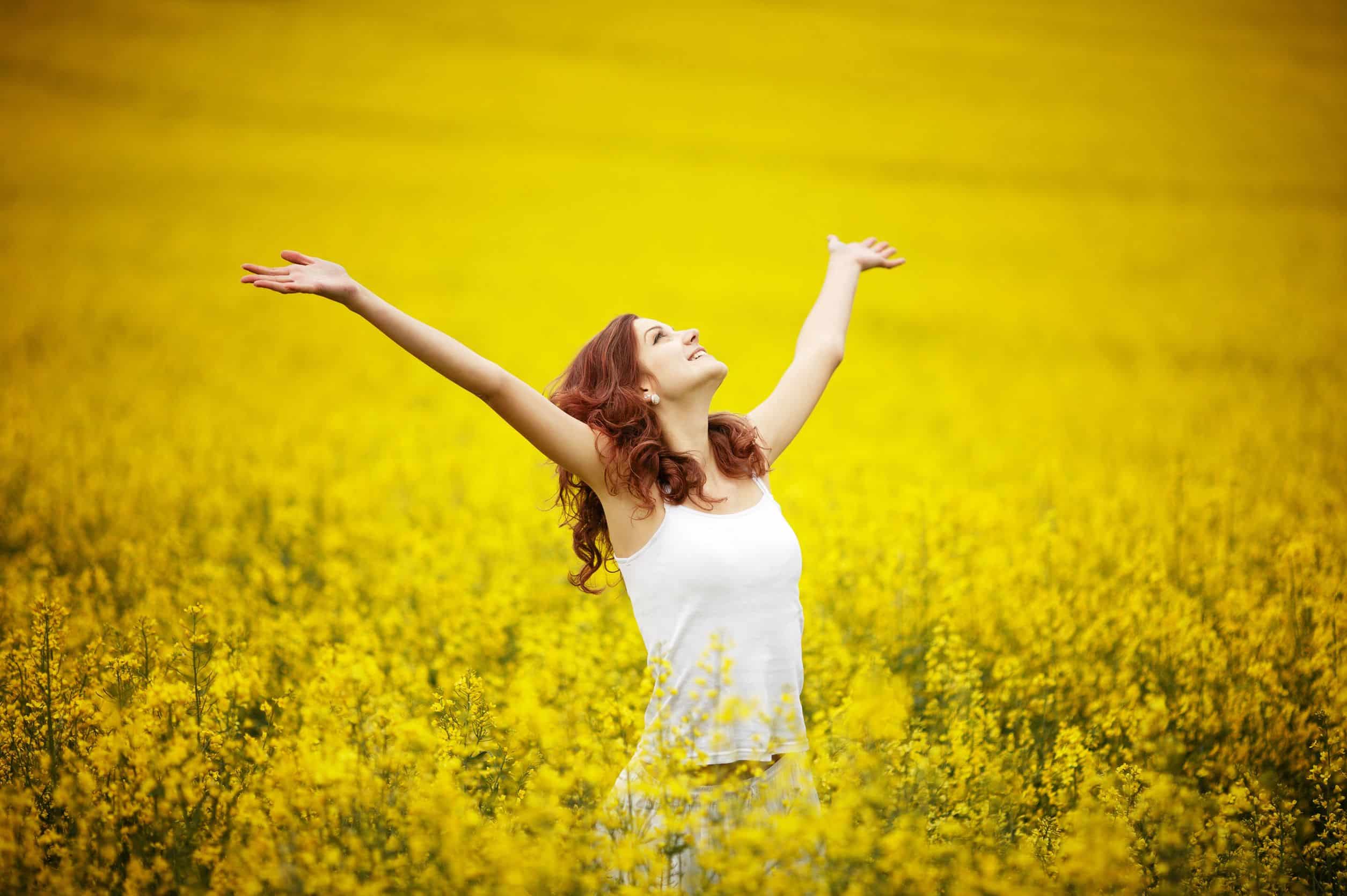 happy woman in a field of yellow flowers