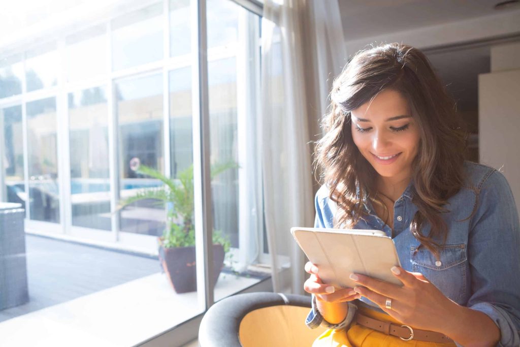 a woman in a sunny room reading content from her favorite brand