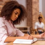 a businesswoman planning her content strategy in a notebook and on a laptop