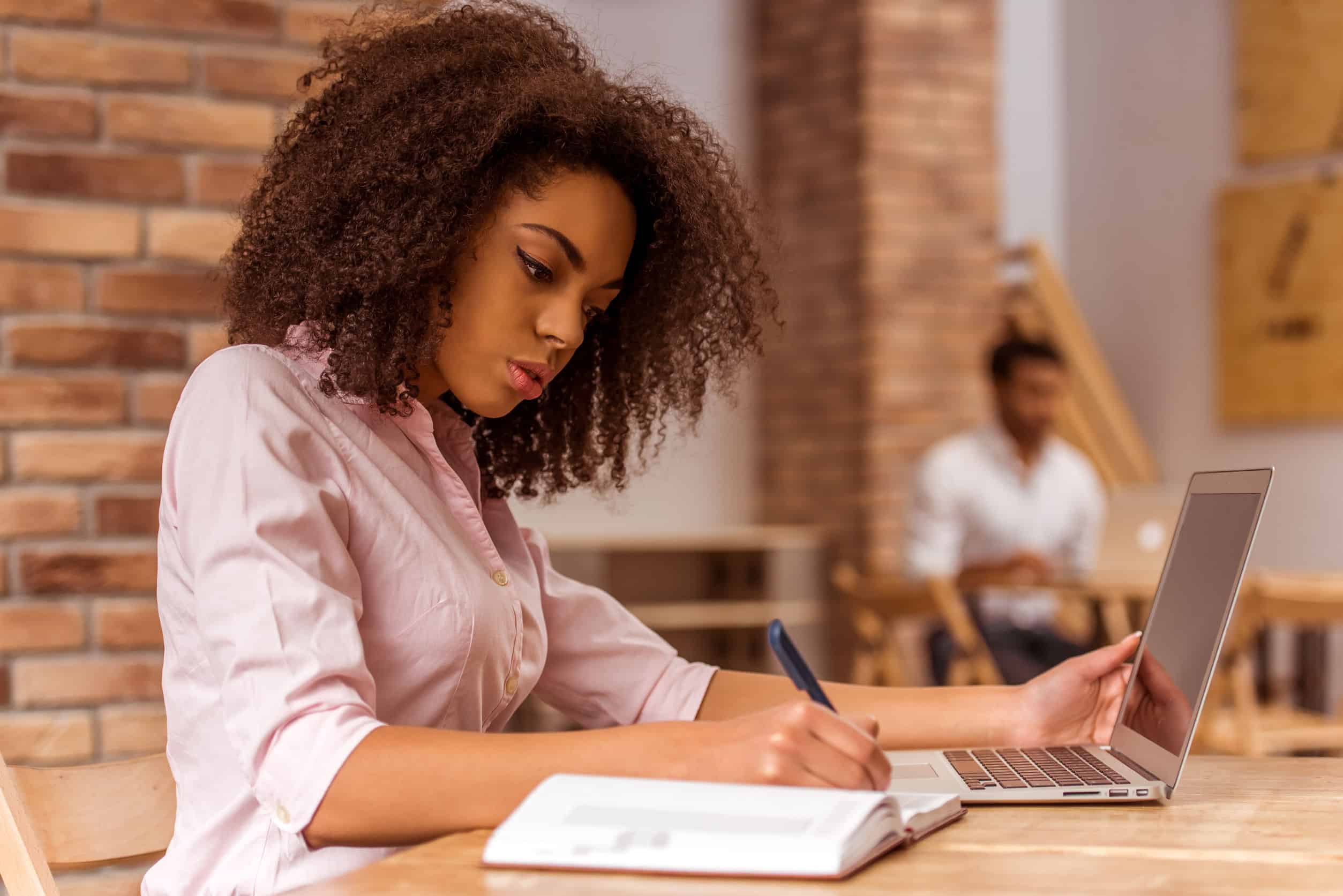 a businesswoman planning her content strategy in a notebook and on a laptop