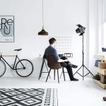 man sitting in an all-white room with minimalist furniture and black decor