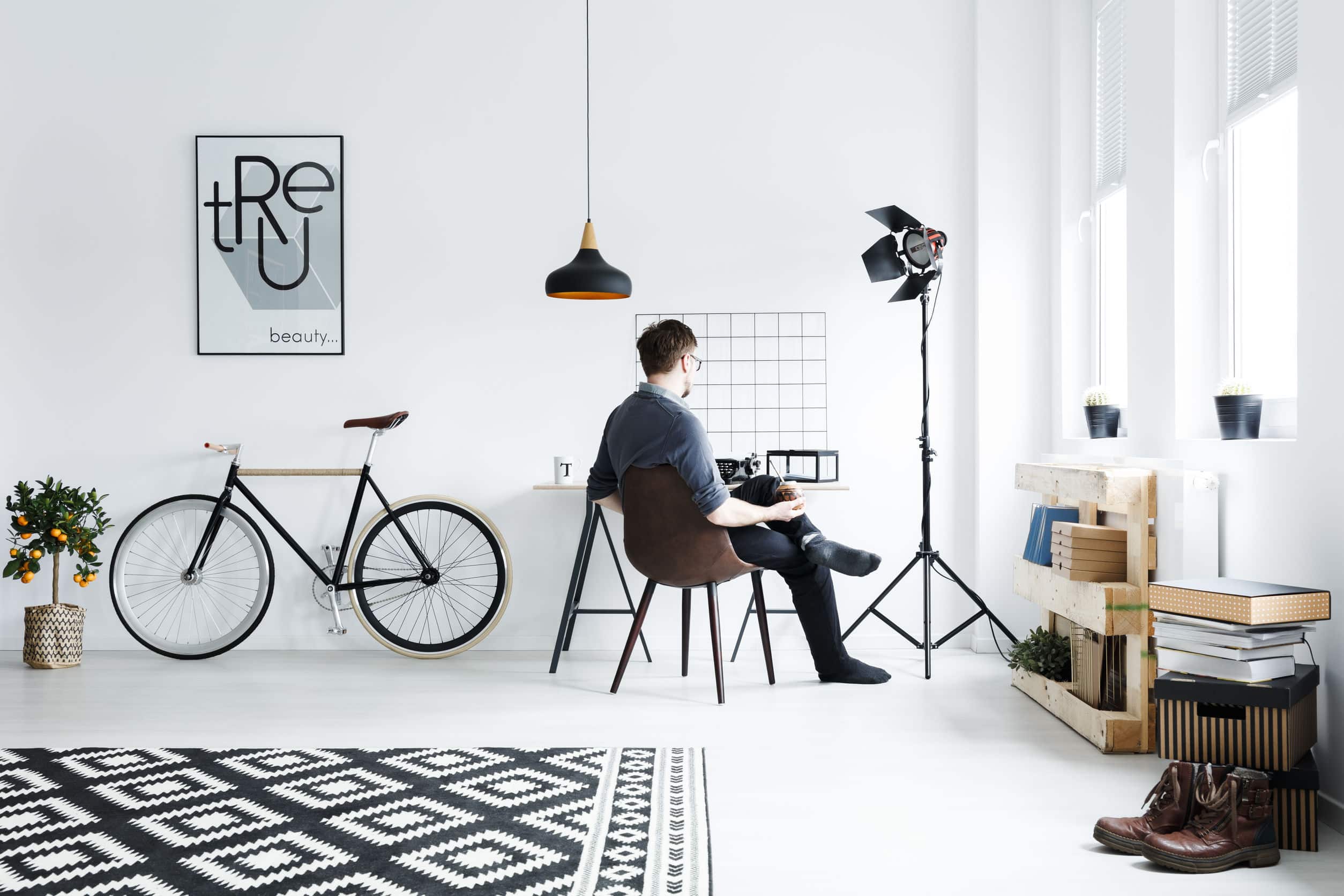 man sitting in an all-white room with minimalist furniture and black decor