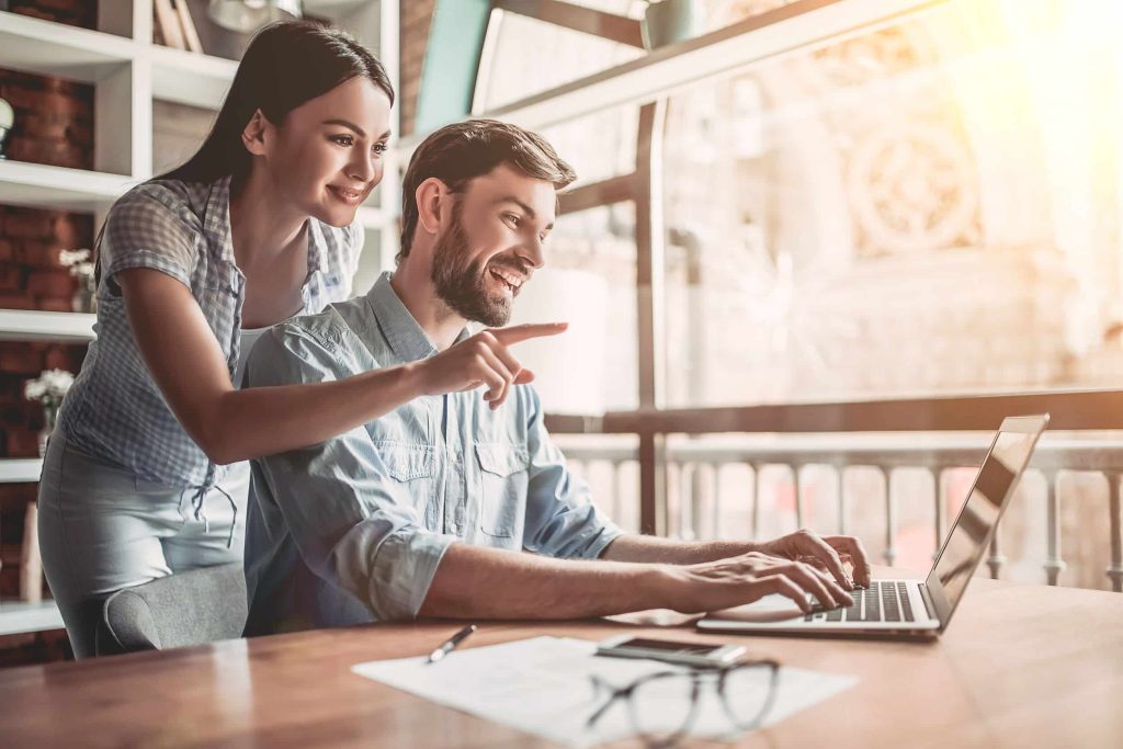 happy couple reading a website on their laptop, about to make a buying decision