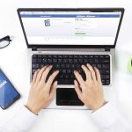 a businessman logging onto Facebook on his laptop