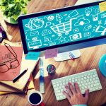 a businessman at his desk with colored pencils, coffee, a plant, and a computer