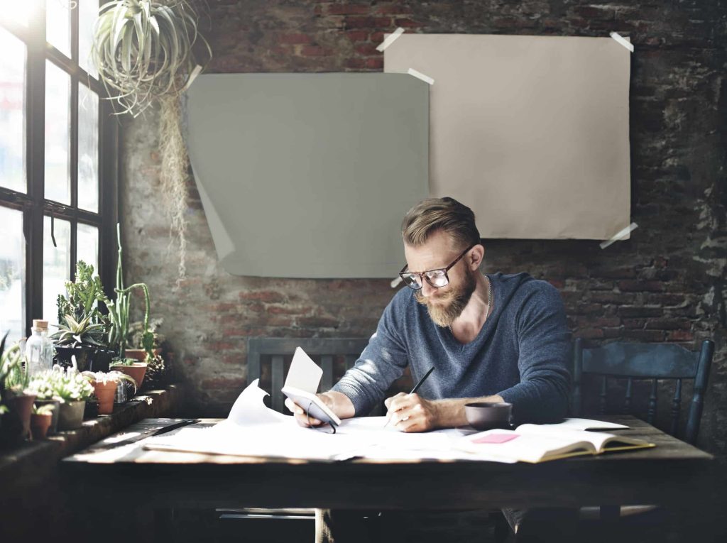 businessman writing out his brand’s message in a brick office room with plants, sunlight, and coffee