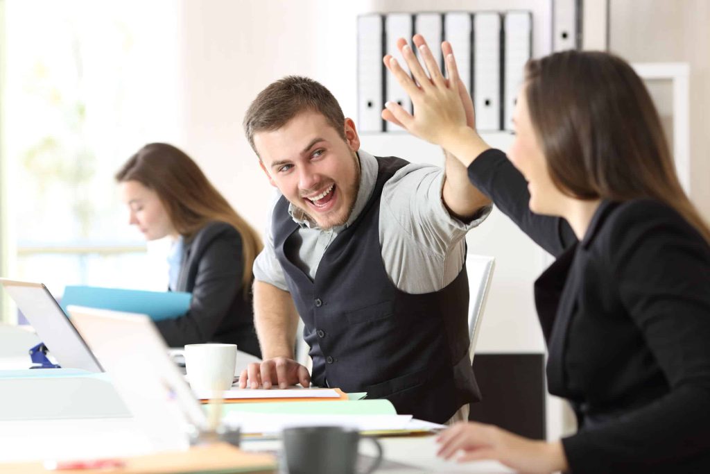 two coworkers high-fiving and supporting each other in the office