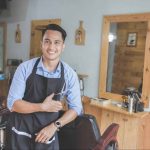 a barbershop owner in front of his chair and mirror