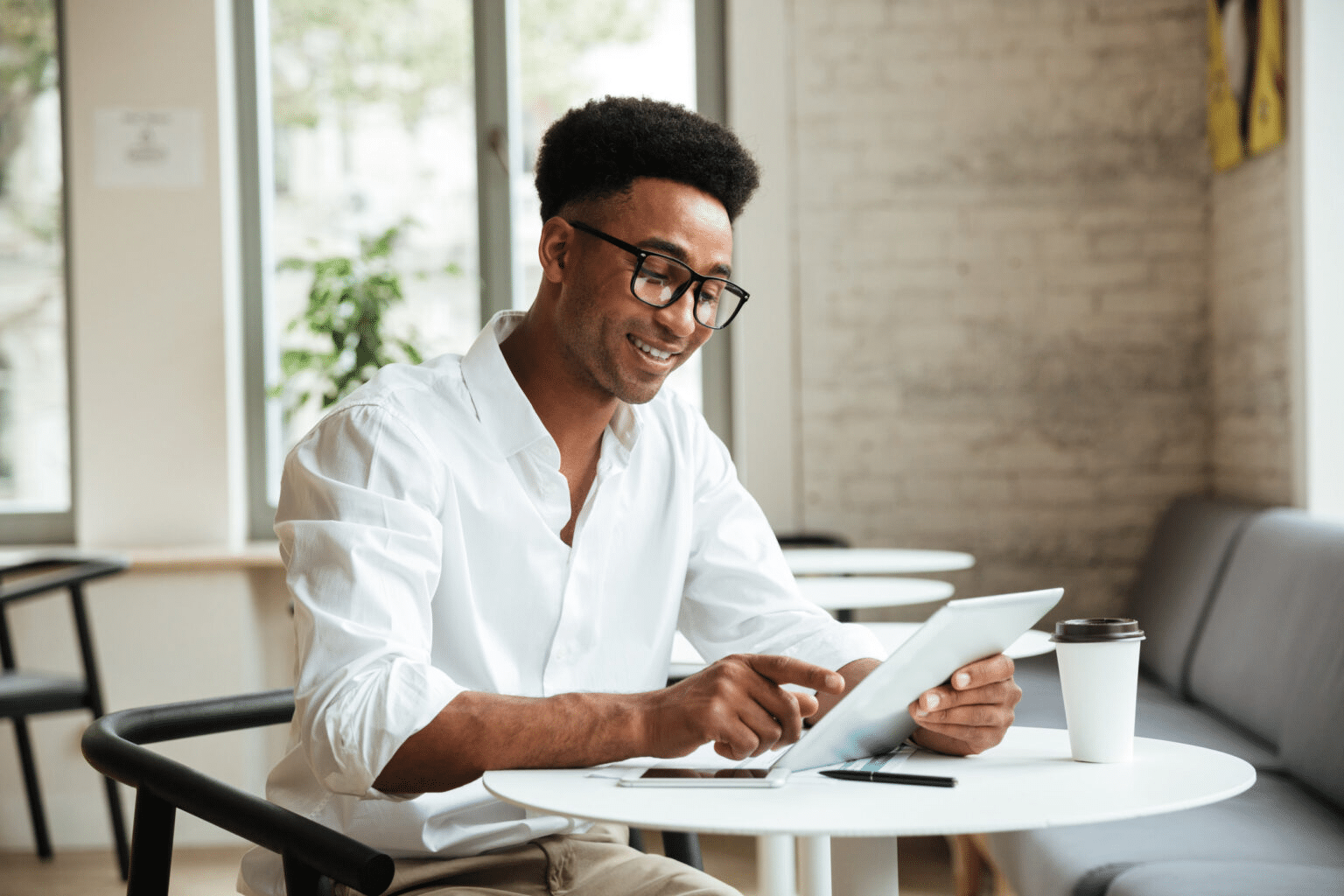 a smiling businessman using his tablet in a coffee shop