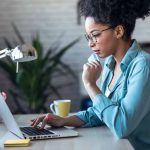 woman sitting alone and using her laptop to make an online purchase