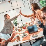 two marketing team members giving a high five over a conference table