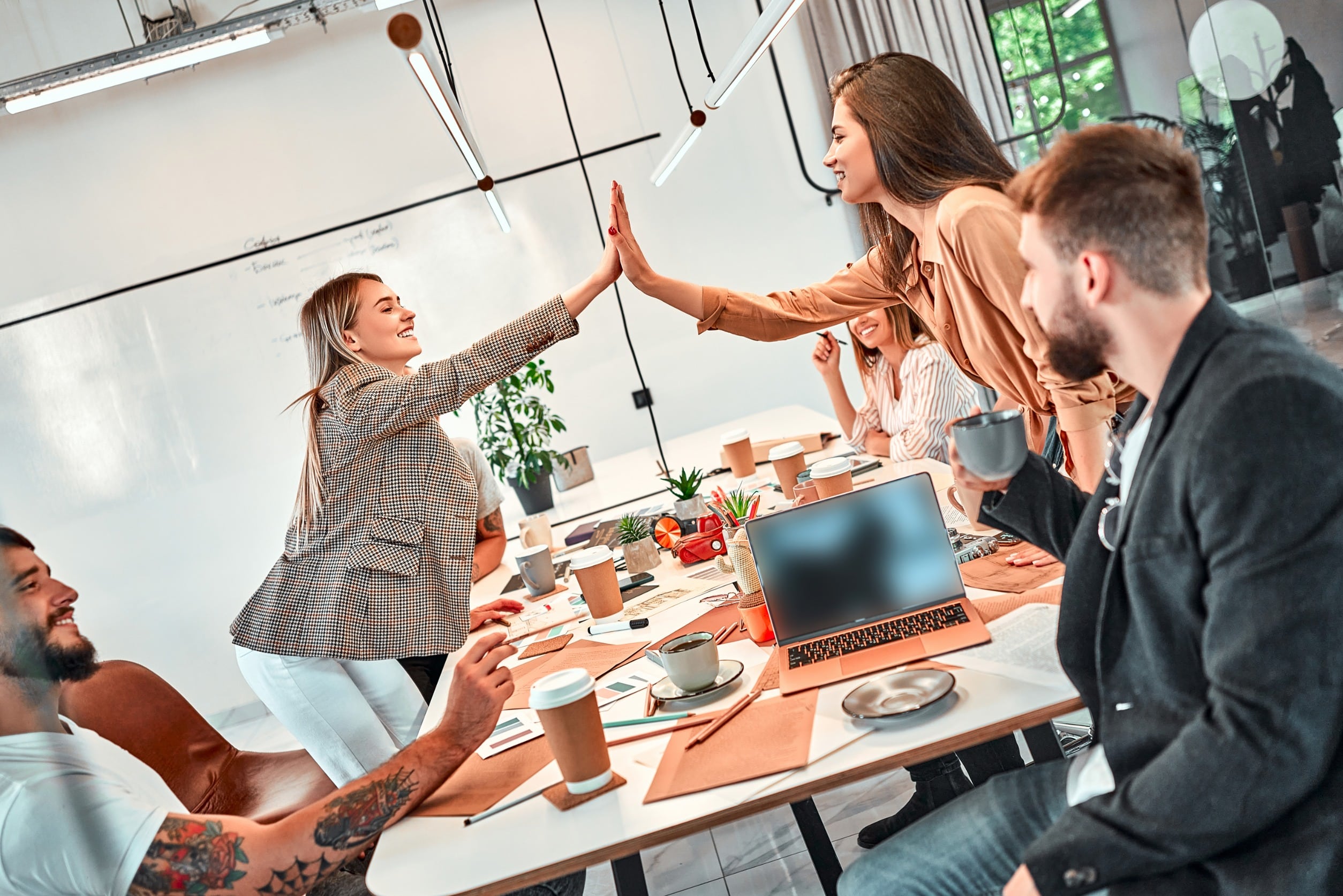 two marketing team members giving a high five over a conference table