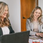 Kelly Rice and Victoria Rayburn talking while on laptops